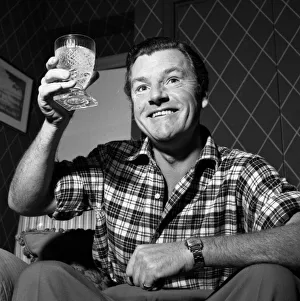 1950s Fashion Prints: Actor Kenneth More raises his glass before having a drink December 1956