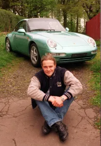 Harley Davidson Prints: Actor Simon Weir poses by the Porsche Targa 911 car May 1997 sitting on ground