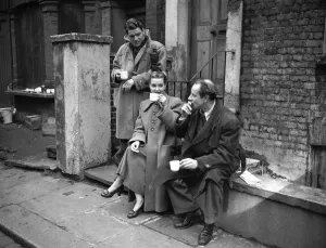 00100 Prints: Actors take a break from filming a scene on location at a butchers shop March 1952