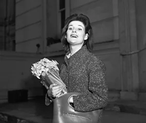 Actress Adrienne Corrie holding a bunch of flowers April 1956