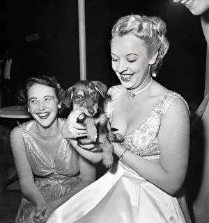00012 Prints: Actress Joy Nichols holding a small dog at a dinner party. July 1952 C3475-001