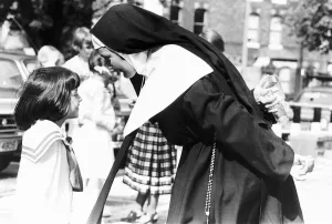 Actress Laura Carr wearing nuns habit talking to a small girl whilst holding a cigarette