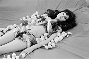 Actress MAdeline Smith lying on a bed covered with garlic and lettuce