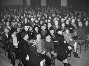 Shelter Prints: Air raid victims together in a hall or lounge during a local event or speech regarding