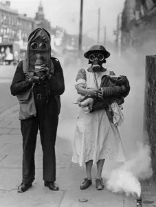 Gas Masks Prints: Air raid warden with nurse and baby in arms seen demonstrating the new gas helmet during