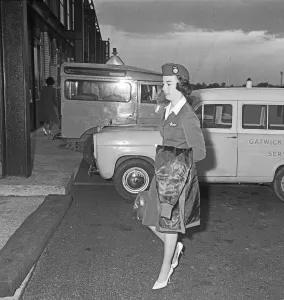 01219 Prints: An Air Stewardess of Overseas Aviation walk towards the terminal at Gatwick Airport after