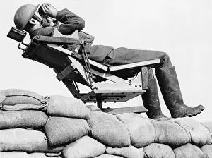Observer Prints: An aircraft observer lies back in a chair on top of a sand bag enforcement scanning