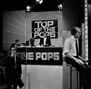 Alan Freeman, (black jacket, white roll neck sweater, sitting behind the microphone
