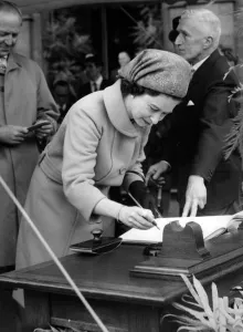 Alderman John grundy steadies the page as Queen Elizabeth II signs the visitors book