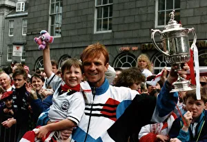 Alex McLeish of Aberdeen Football Club in the street holding up his son in one hand