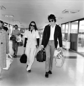 American actor Warren Beatty at Heathrow Airport with Michelle Phillips. May 1975