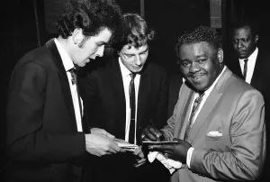 Autograph Prints: American rock and roll star Fats Domino signs autographs for fans on the stage of