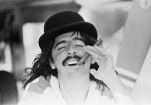 American rock singer Alice Cooper wearing a bowler hat and smoking a cigar during his