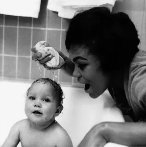 American singer and actress Eartha Kitt, photographed giving her baby girl Kitt a bath