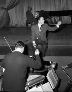 00086 Prints: American singer and film star Frank Sinatra sitting on stage during rehearsals