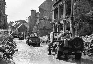 Jeep Prints: American troops in jeeps making their way through a bomb damaged Normandy town in