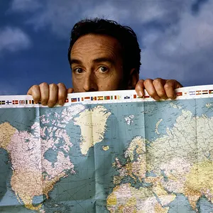 Angus Deayton TV presenter peering looking over map of the world