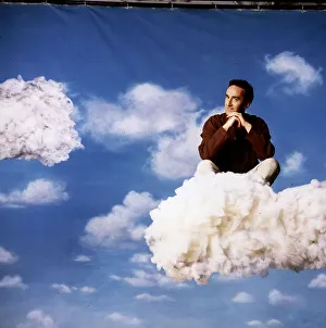 Angus Deayton TV presenter sitting on cloud in sky background back drop