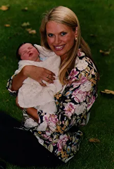 Anneka Rice holding baby smiling sitting on grass wearing flowery print shirt TV