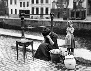 Images Dated 13th September 2012: Antwerp Belgium 1914 - A woman weeps at the roadside beside a table some pots
