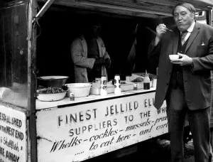 Stall Prints: Arthur Mullard enjoys some jellied eels in the West End December 1974