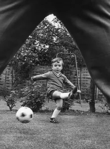 00325 Prints: Aston Villa footballer Ron Wylie playing football with his son Nigel in the garden of
