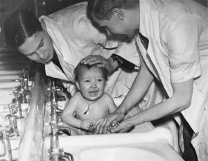 A baby gets a bath in the sink. Picture taken 4th January 1941