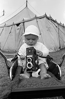 A baby sitting with a Rolleiflex camera at Skelton annual baby show. Circa 1973