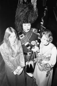 Bagpipes Prints: Two ball goers pose with the piper at the Birmingham and West Midlands Scottish Society