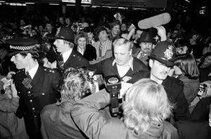 Barry Manilow and Roberta Kent surrounded by his many fans as he leaves Heathrow Airport