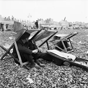 00594 Prints: Beach scene Brighton, East Sussex. Holidaymaker seek shelter from a summer shower