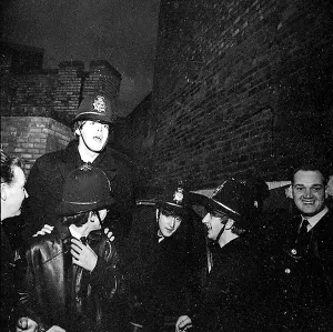 The Beatles clowning around, dressed in policemen helmets used to smuggle them into