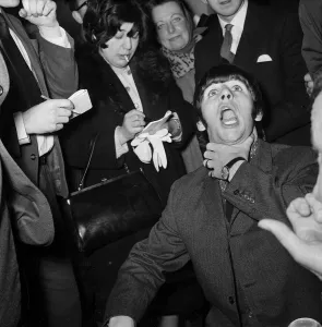 Beatles drummer Ringo Starr shows off his tonsils to the press before entering