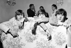 Group Shot Prints: Beatles Files 1964. Ringo Starr John Lennon Paul McCartney lounge about on a hotel sofa