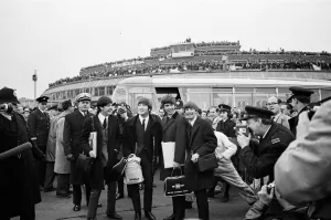 The Beatles at Heathrow Airport in front of a packed roof top on the terminal building