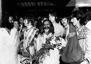The Beatles with the Maharishi Mahesh Yogi who is clutching bundles of flowers Beatles