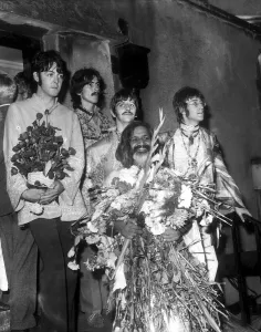 Hippy Prints: The Beatles with the Maharishi Mahesh Yogi who is clutching bundles of flowers Beatles