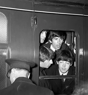The Beatles peer from a train carriage window at Paddington Station, London