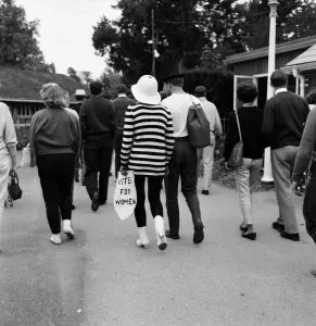 1961 Prints: Beaulieu Jazz Festival. A young girl in a striped sweater carries a notice saying