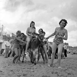 Holidaymakers Prints: Beauty contest girls playing with a donkey on the beach at Ramsgate