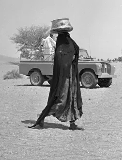 Middle East Prints: A bedouin woman seen here wearing traditional dress collecting water. July 1965