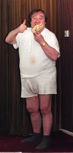 Bernard Manning comedian eating a Walls Arctic Roll dessert. September 1997