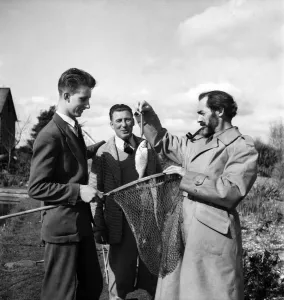 Kneeling Prints: Bernard Venables Daily Mirror fishing expert seen here discussing the catch with a fellow