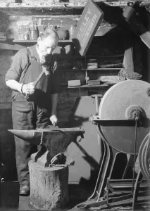 Hammer Prints: A Blacksmith works in his forge, hammering out a metal sheet on his anvil. Circa 1940