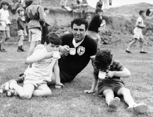 00328 Prints: Bobby Smith of Tottenham Hotspur drinking a cup of tea with two young boys during a