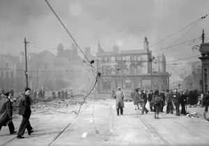Bomb damage in Liverpool, civilians walking under damaged tram power lines after