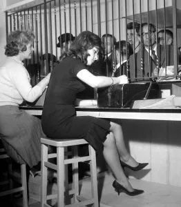 Bookies clerks taking bets from punters at a busy betting shop in Soho