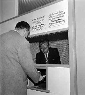 A bookmaker accepting a bet from a punter at Eric Barbers betting shop in Old Trafford