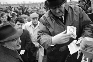 Bookmaker taking bets from crowds of punters before the race at Leopardstown in Ireland