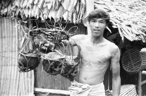 00671 Prints: A Borneo headhunter tribesman seen here holding up a basket of human skulls